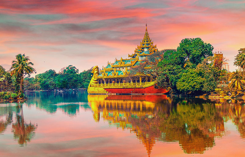 golden temple by a lake surrounded by trees and pink and blue skies