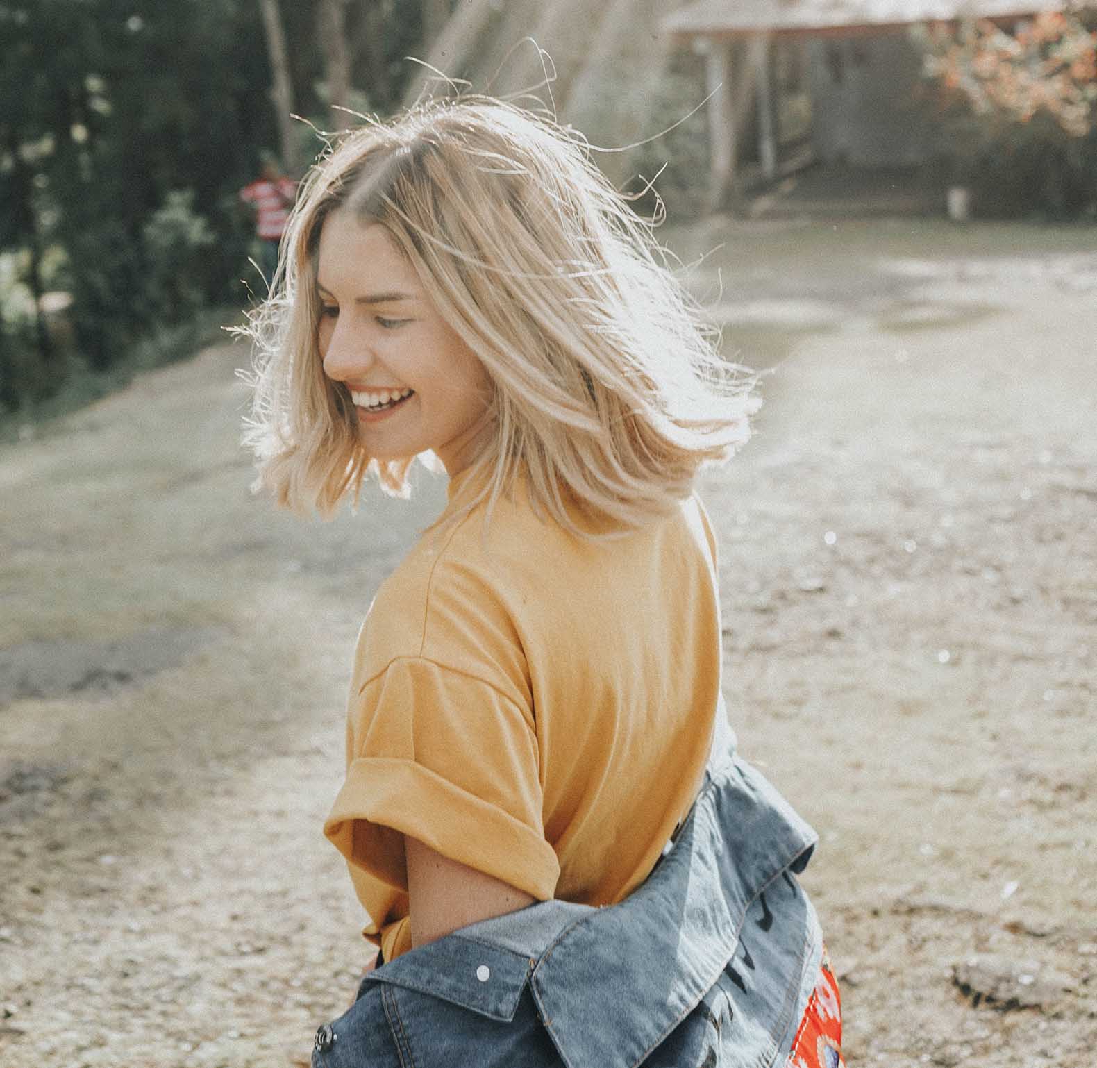 blonde happy woman with a yellow t-shirt seen from the side with the sun shining on her